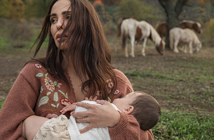 Тя е с черна копринена рокля тип комбинезон с дантела